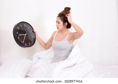 Asian Woman Too Late Wake Up Hold Big Black Clock On Bed In Bedroom At Home.