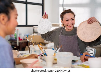 Asian woman learning color painting self-made pottery plate with friends at home. Confidence female enjoy handicraft activity lifestyle hobbies ceramic sculpture painting workshop at pottery studio - Powered by Shutterstock