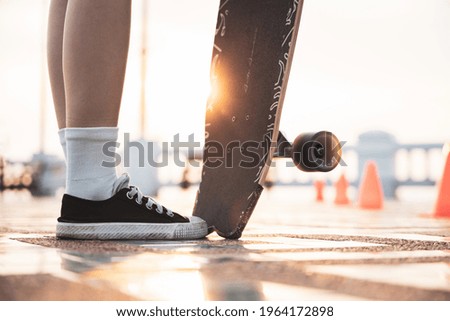 Asian woman leg on surf skate or skate board in outdoor Park at sunset. sport training for trendy people.