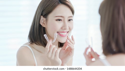 Asian woman look at the mirror with invisible braces in the morning
