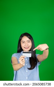 Asian Woman Looking At Camera While Holding Atm Card With Hand Gesture Pointing