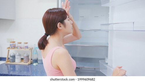 Asian Woman Looking At Empty Shelf In Fridge And She Feel Upset