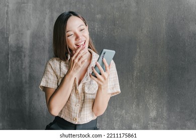 Asian Woman Looking At Her Phone And Excited About Victory Cheerful Smiling Girl