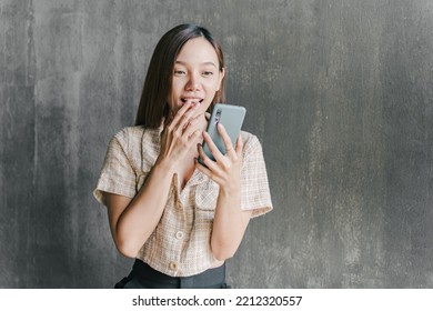 Asian Woman Looking At Her Phone And Excited About Victory Cheerful Smiling Girl