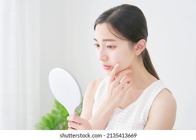 Asian woman looking in the mirror - Shutterstock ID 2135413669