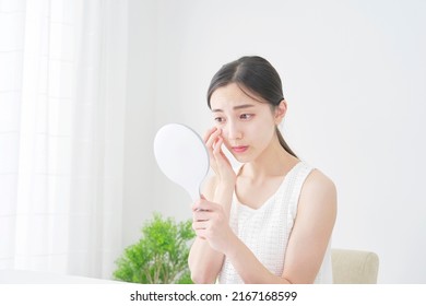 Asian woman looking in the mirror at home - Shutterstock ID 2167168599