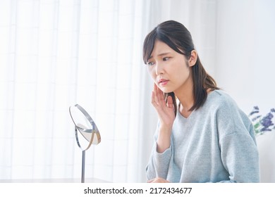 Asian woman looking in the mirror at home - Shutterstock ID 2172434677