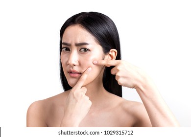 Asian woman looking at pimple on face. Young Woman try to remove her pimple. Woman skin care concept. Isolated on white background.