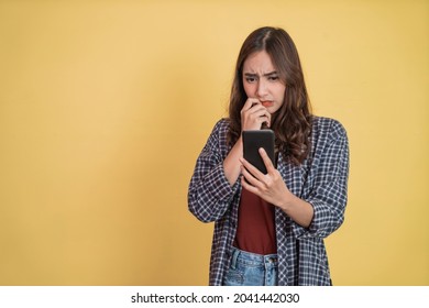 asian woman looking at screen while using a smartphone with worried expression with copyspace