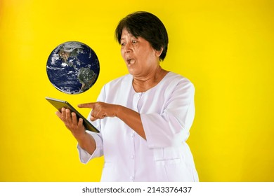 Asian Woman Looking At Split Screen With World On Yellow Background. Elements Of This Image Furnished By NASA