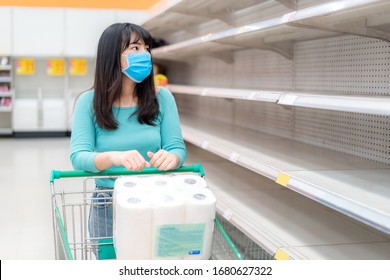 Asian woman looking at Supermarket empty toilet paper shelves amid COVID-19 coronavirus fears, shoppers panic buying and stockpiling toilet paper preparing for a pandemic. - Shutterstock ID 1680627322