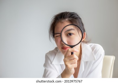 Asian Woman Looking Through Magnifying Glass, Searching Or Investigating Something.