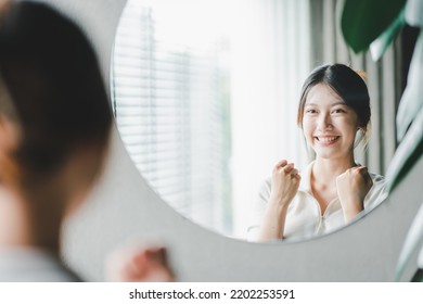 Asian woman looking through the mirror and confident of herself. cheer yourself up