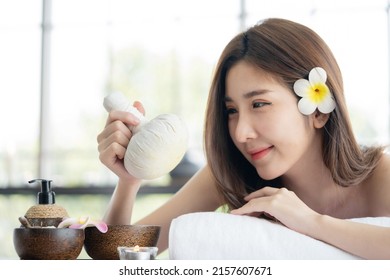 Asian Woman Lying Down on Massage Bed Holding Spa  Herbal Compress Ball  Waiting For Body Care Treatment
