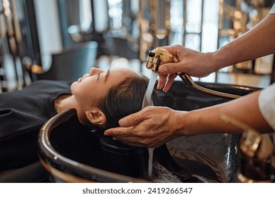 Asian woman lying down on salon washing bed getting hair washed in hair salon by stylist, Hairdresser shampoo the customer hair then washing hair - Powered by Shutterstock