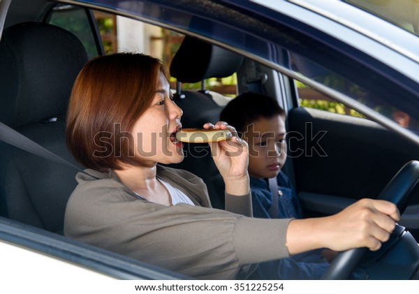Asian woman make up and eat during driving. Road\
safety concept.