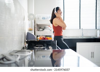 Asian woman making fruit smoothie after exercise. she is listening to music - Powered by Shutterstock