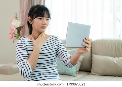 Asian woman making video call with her doctor with her feeling sore throat on digital tablet online healthcare digital technology service consultation while staying at home.  - Powered by Shutterstock