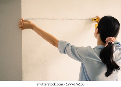 Asian woman measuring the size of the wall
 - Powered by Shutterstock