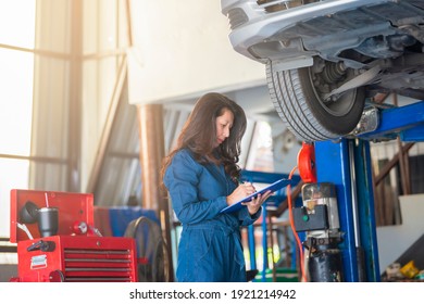 Asian Woman Mechanic Writing To The Clipboard At The Tire Change At The Auto Repair Shop. 