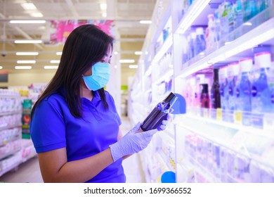 Asian Woman In Medical Face Mask And Medical Gloves Holding Medicine Bottle In The Drug Store Patient Shopping Pills For Antihistamines Antipyretics And Cough Syrup.covid-19 Spreading Outbreak