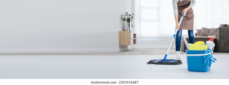 Asian woman mopping tile floor at living room while doing cleaning at home during Staying at home using free time about their daily housekeeping routine. - Powered by Shutterstock