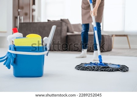 Asian woman mopping tile floor at living room while doing cleaning at home during Staying at home using free time about their daily housekeeping routine.