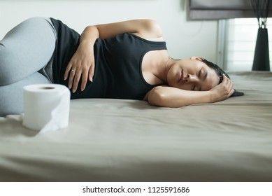 Asian woman with morning sickness and sleeping,Pregnant female nausea vomiting in bedroom,Indigestible