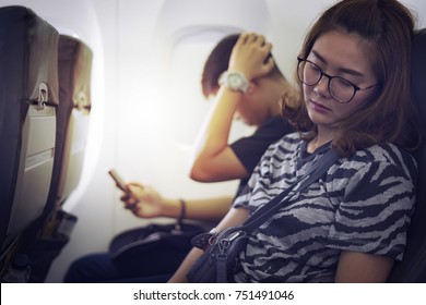 Asian Woman Is Napping On Uncomfortable Seat While Traveling By Airplane. Commercial Transportation By Planes.
