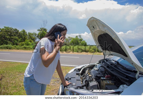 Asian woman need for help  with a broken car with\
open hood.\
