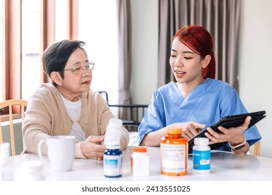 Asian woman nurse holding a medicine bottle and telling information to Asian senior woman before administering medication. Caregiver visit at home. Home health care and nursing home concept. - Powered by Shutterstock