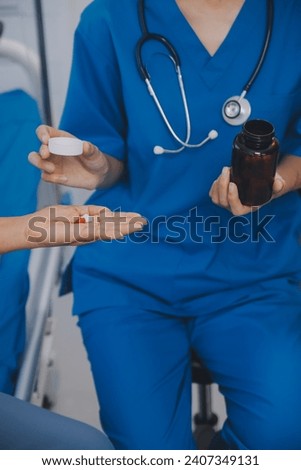 Asian woman nurse holding a medicine bottle and telling information to Asian senior woman before administering medication. Caregiver visit at home. Home health care and nursing home concept. Foto stock © 