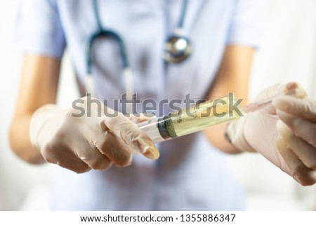 Asian woman nurse in white uniform wearing latex gloves is holding syringe needle with yellow liquid medicine inside on white background. 