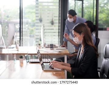 Asian Woman Office Worker Wearing Face Mask Working In The New Normal Office And Doing Social Distancing During Coronavirus COVID-19 Pandemic