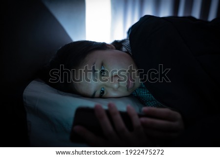 Asian woman on bed late at night and using mobile smartphone before sleep
