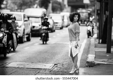 Asian woman on a busy highway. Black-and-white.