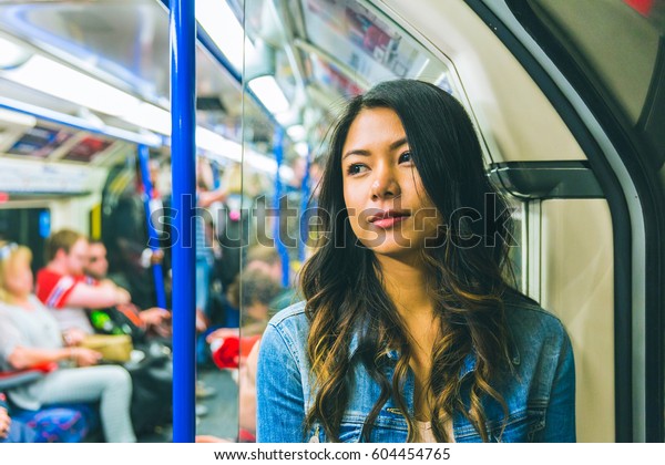 ロンドンの管の上のアジア人女性 カメラから離れ 通勤しながら電車に寄りかかる美しい若い女性のポートレート ライフスタイルと交通のコンセプト の写真素材 今すぐ編集