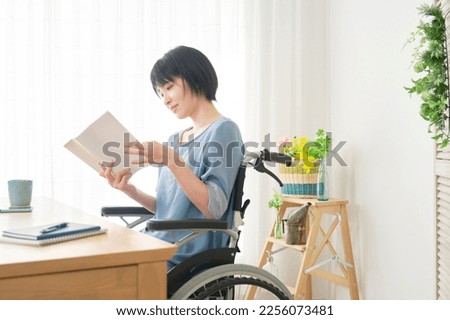 Asian woman on the wheelchair reading the book at home