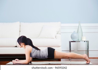 Asian Woman On A Yoga Mat Doing The Dolphin Plank Pose.