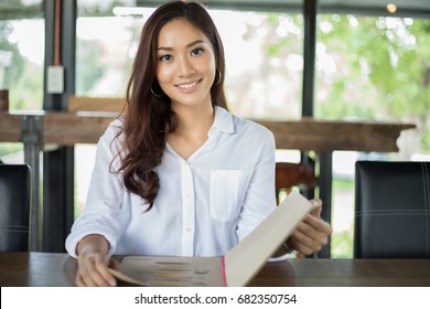 Asian Woman Open Menu For Ordering In Coffee Cafe And Restaurant And Smiling For Happy Time 