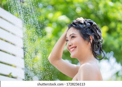 Asian Woman Outdoor Shower She Uses Her Hands To Combine Her Hair And Is Smiling.