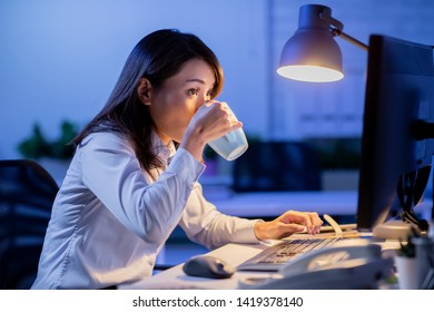 Asian Woman Overtime Work And Drink Tea Or Coffee In The Office