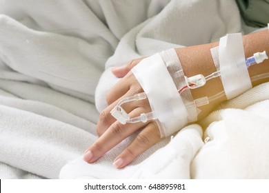 Asian Woman Patient Hand On IV Drip With Saline Solution, Fluid Replacement Therapy