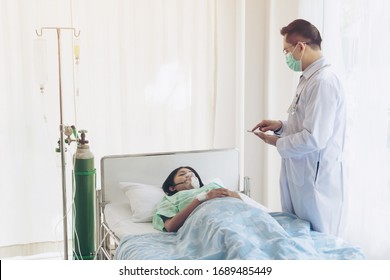 Asian Woman Patients Wearing Face Mask Oxygen Respirator In Quarantine Room Hospital ,doctor Is Recording The Treatment Information, Quarantine To Protect Spread Corona Virus Covid-19