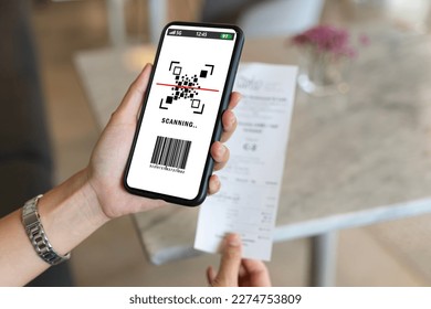 Asian woman paying electricity bill hand holding smart phone scanning code on paper, scan the qr code. Scan to get discounts. Using a phone to transfer money, paying money online without cash concept. - Shutterstock ID 2274753809