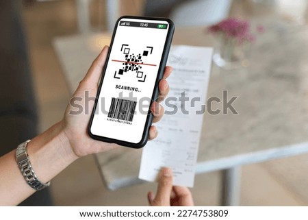 Asian woman paying electricity bill hand holding smart phone scanning code on paper, scan the qr code. Scan to get discounts. Using a phone to transfer money, paying money online without cash concept.
