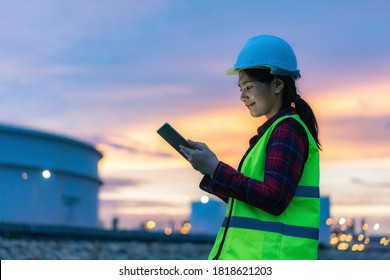 Asian woman petrochemical engineer working at night with digital tablet Inside oil and gas refinery plant industry factory at night for inspector safety quality control.
 - Powered by Shutterstock