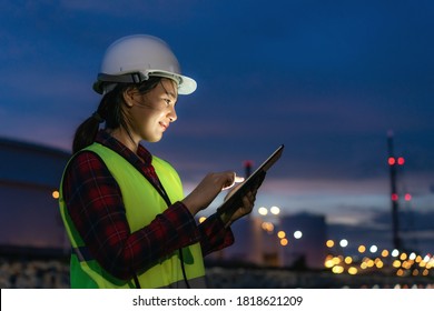 Asian woman petrochemical engineer working at night with digital tablet Inside oil and gas refinery plant industry factory at night for inspector safety quality control. - Shutterstock ID 1818621209