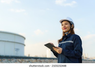 Asian Woman Petrochemical Engineer Working With Digital Tablet Inside Oil And Gas Refinery Plant Industry Factory At Night For Inspector Safety Quality Control.
