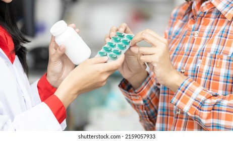 Asian woman pharmacist give medicine and explain the direction to use to his patient asian woman at the pharmacy drugstore, Asian female pharmacist explain how to use drug. - Shutterstock ID 2159057933